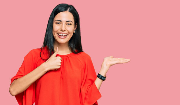 Beautiful young woman wearing casual clothes showing palm hand and doing ok gesture with thumbs up, smiling happy and cheerful