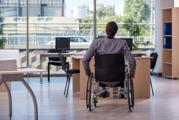 Young male employee in wheel-chair working in the office