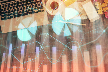 Financial market graph and top view computer on the desktop background. Double exposure. Investment concept.
