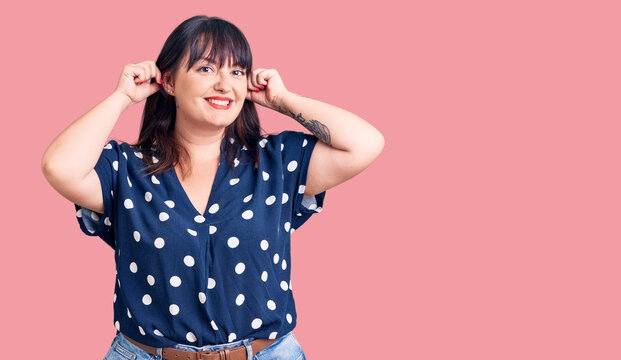 Young plus size woman wearing casual clothes smiling pulling ears with fingers, funny gesture. audition problem