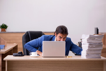 Young male employee unhappy with excessive work in the office