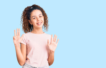 Beautiful kid girl with curly hair wearing casual clothes showing and pointing up with fingers...