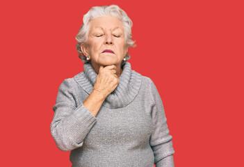 Senior grey-haired woman wearing casual winter sweater touching painful neck, sore throat for flu, clod and infection