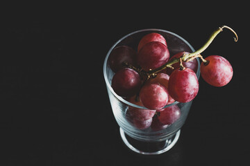 Red grapes, large bunch of fruits, fresh and tasty simple food on a dark background in a fancy minimal composition