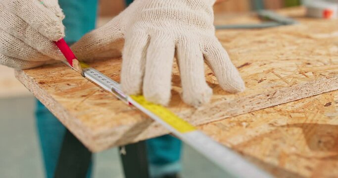 Close up of a hardworking professional carpenter holding a ruler and pencil while making a board center in a carpentry workshop. A bearded DIY enthusiast measures wood. There are a locksmith table and