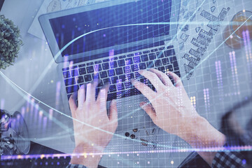 Double exposure of man's hands typing over laptop keyboard and forex chart hologram drawing. Top view. Financial markets concept.