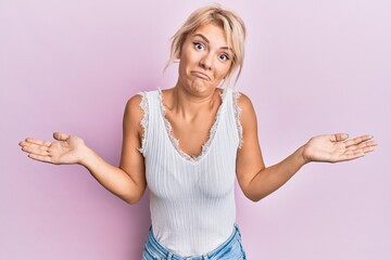 Young blonde girl wearing casual clothes clueless and confused expression with arms and hands...