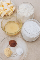 Glass of flour, glass of powdered sugar, pieces of butter, spices and honey on tablecloth. Ingredients for cooking.