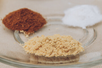 Grated cinnamon, graded ginger and sugar powder close-up on glass plate. Macro shot. Selective focus.