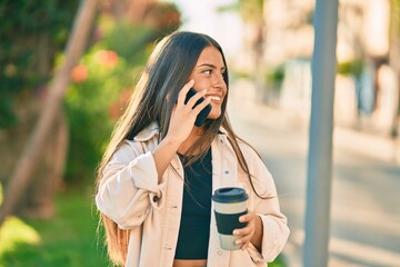 Young hispanic girl smiling happy talking on the smartphone and drinking take away coffee at the...