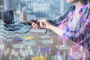 Double exposure of businesswoman hands typing on computer and forex graph hologram drawing....