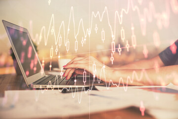 Double exposure of businesswoman hands typing on computer and forex chart hologram drawing....