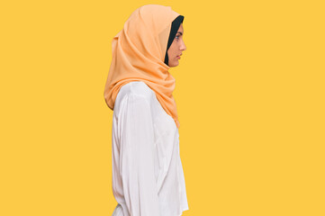 Young brunette woman wearing traditional islamic hijab scarf looking to side, relax profile pose with natural face with confident smile.