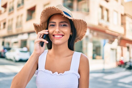Young latin girl wearing summer style talking on the smartphone at street of city.