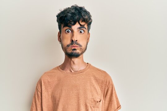 Young hispanic man wearing casual clothes puffing cheeks with funny face. mouth inflated with air, crazy expression.