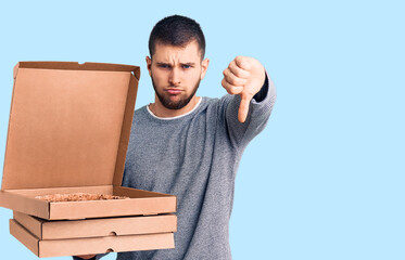 Young handsome man holding delivery italian pizza boxes with angry face, negative sign showing...