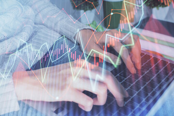 Double exposure of woman hands typing on computer and forex chart hologram drawing. Stock market...