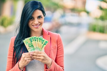 Young beautiful businesswoman smiling happy holding russian rubles banknotes at the city.