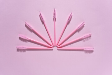 Creative concept beauty fashion photo of lashes extensions brush on pink background.