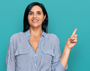 Young caucasian woman wearing casual clothes with a big smile on face, pointing with hand finger to the side looking at the camera.