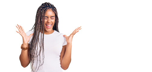 Young african american woman with braids wearing casual clothes celebrating mad and crazy for success with arms raised and closed eyes screaming excited. winner concept