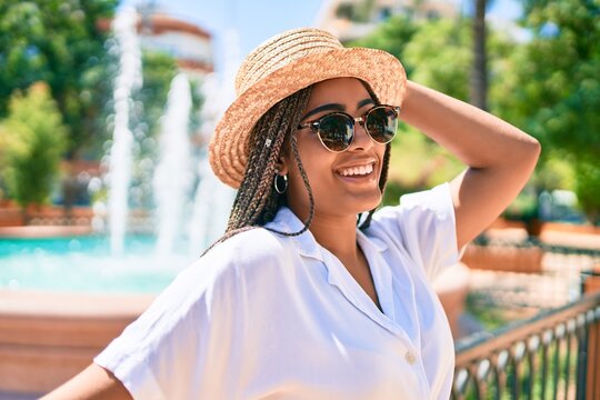Young african american woman with braids wearing sunglasses and smiling happy outdoors on a sunny day of summer