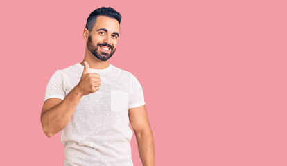 Young hispanic man wearing casual clothes doing happy thumbs up gesture with hand. approving expression looking at the camera showing success.