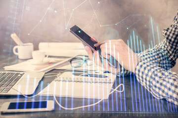 Fototapeta premium Double exposure of man's hands holding and using a digital device and forex graph drawing. Financial market concept.