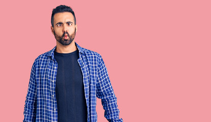 Fototapeta premium Young hispanic man wearing casual clothes making fish face with lips, crazy and comical gesture. funny expression.
