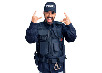 Young hispanic man wearing police uniform shouting with crazy expression doing rock symbol with...