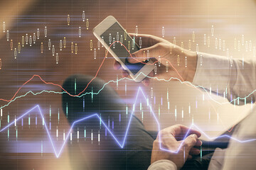 Double exposure of man's hands holding and using a digital device and forex graph drawing. Financial market concept.
