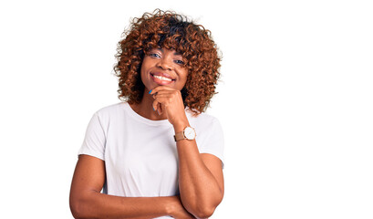 Fototapeta na wymiar Young african american woman wearing casual white tshirt looking confident at the camera with smile with crossed arms and hand raised on chin. thinking positive.