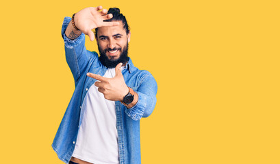 Young arab man wearing casual denim shirt smiling making frame with hands and fingers with happy face. creativity and photography concept.