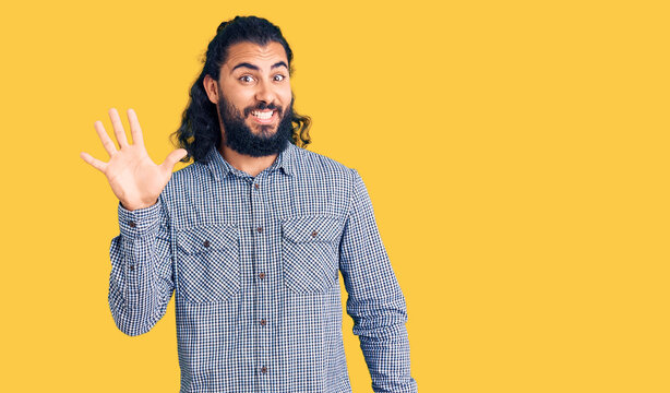 Young arab man wearing casual clothes showing and pointing up with fingers number five while smiling confident and happy.