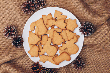 Tasty Christmas gingerbread cookies on the white plate on a sackcloth.