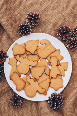 Tasty Christmas gingerbread cookies on the white plate on a sackcloth.