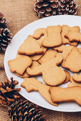 Tasty Christmas gingerbread cookies on the white plate on a sackcloth.