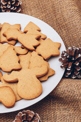 Tasty Christmas gingerbread cookies on the white plate on a sackcloth.