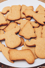 Tasty Christmas gingerbread cookies on the white plate on a sackcloth.
