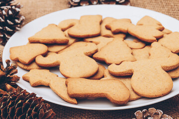 Tasty Christmas gingerbread cookies on the white plate on a sackcloth.