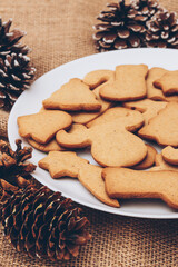 Tasty Christmas gingerbread cookies on the white plate on a sackcloth.