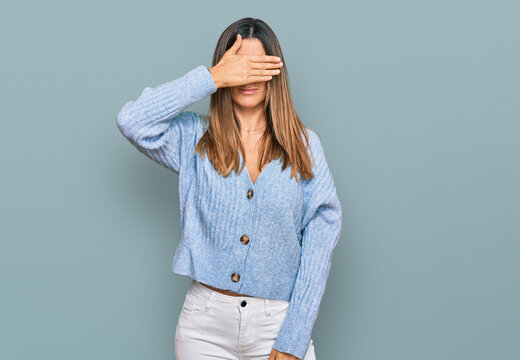 Young woman wearing casual clothes covering eyes with hand, looking serious and sad. sightless, hiding and rejection concept