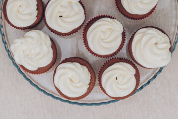 Delicious chocolate cupcakes with swirled frosting cream on top on the bright tablecloth. Top view.