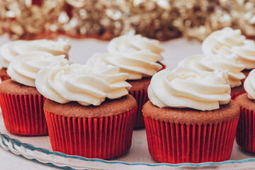 Delicious chocolate cupcakes with swirled frosting cream on top. Cupcakes on a glass tray with colorful holiday background.