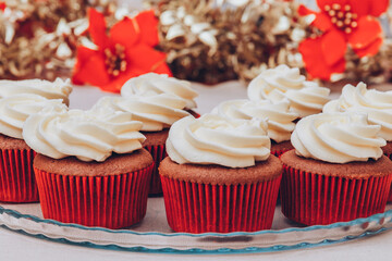 Delicious chocolate cupcakes with swirled frosting cream on top. Cupcakes on a glass tray with colorful holiday background.