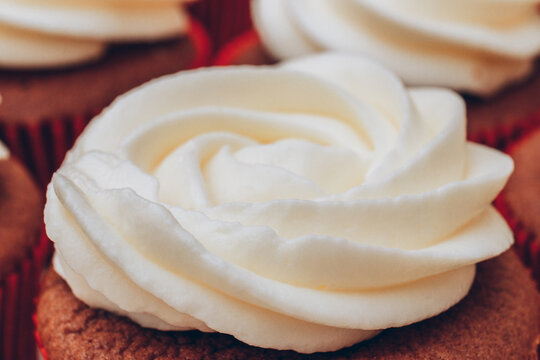 Delicious chocolate cupcakes with swirled frosting cream on top close up. Macro shot. Selective focus.