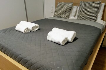 View of the made-up bed with pillows in the bedroom with towels on it.