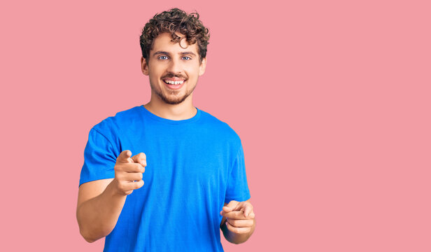 Young handsome man with curly hair wearing casual clothes pointing fingers to camera with happy and funny face. good energy and vibes.