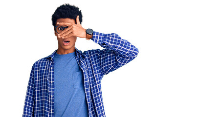 Young african american man wearing casual clothes and glasses peeking in shock covering face and eyes with hand, looking through fingers with embarrassed expression.