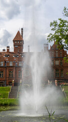 Tume, Latvia_- July 7, 2020: Brick Medieval Jaunmoku Castle at Pond. The Jaunmokas Manor Park. This...